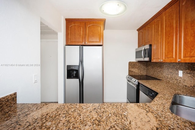 kitchen with stainless steel appliances, brown cabinets, light stone counters, and decorative backsplash