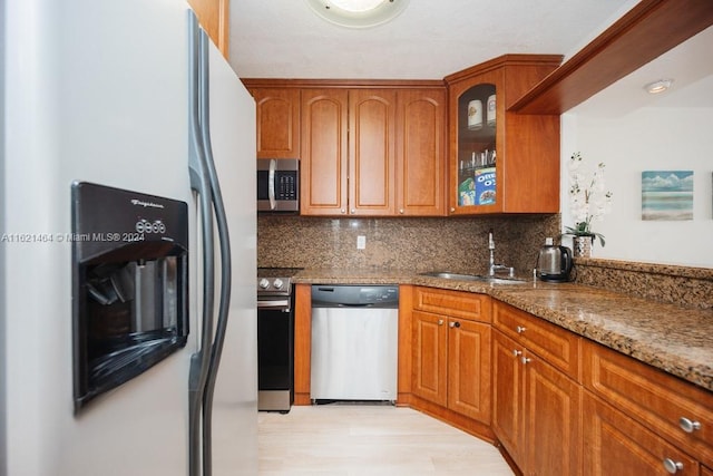 kitchen with stainless steel appliances, stone counters, a sink, and tasteful backsplash