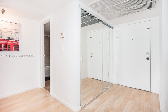 hallway with baseboards, visible vents, and wood finished floors