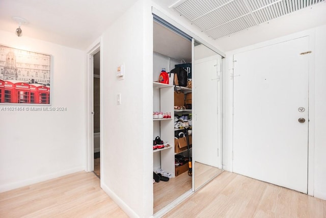 hall with visible vents, baseboards, and wood finished floors