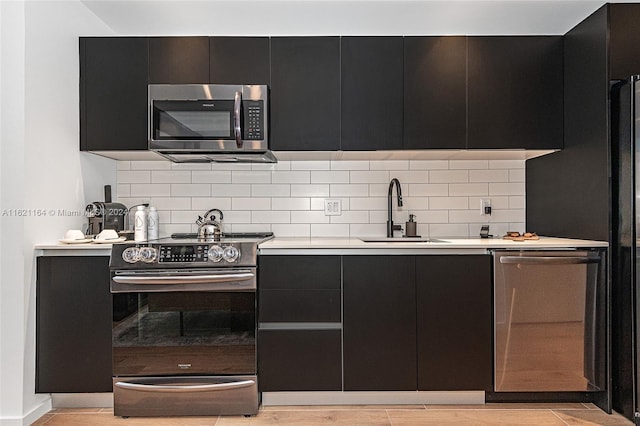 kitchen featuring decorative backsplash, light hardwood / wood-style flooring, appliances with stainless steel finishes, and sink