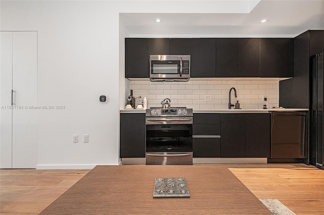 kitchen with sink, light hardwood / wood-style flooring, black appliances, and backsplash