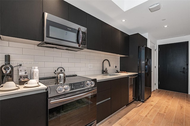 kitchen featuring sink, light hardwood / wood-style flooring, stainless steel appliances, and backsplash