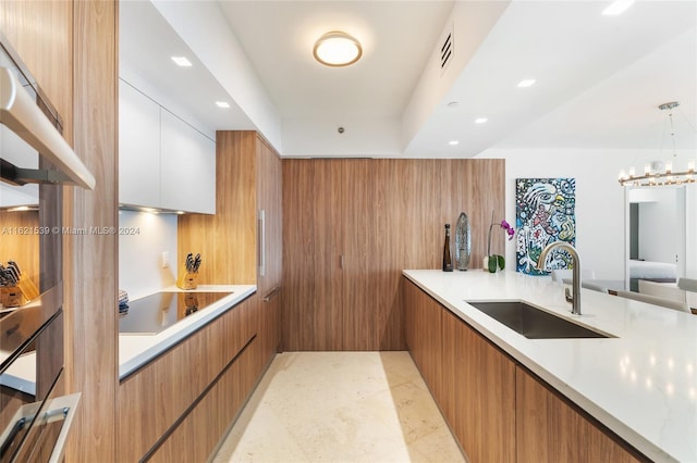 kitchen with sink, black electric stovetop, white cabinets, decorative light fixtures, and a chandelier