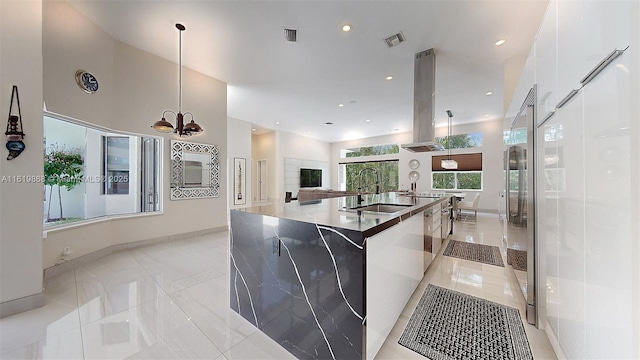 kitchen featuring sink, decorative light fixtures, island range hood, white cabinetry, and a chandelier