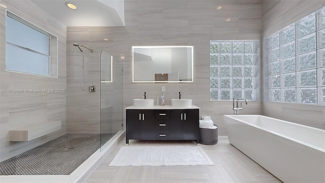 bathroom with tile patterned flooring, vanity, tile walls, and independent shower and bath