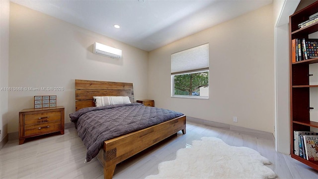 bedroom with light hardwood / wood-style flooring and a wall mounted air conditioner