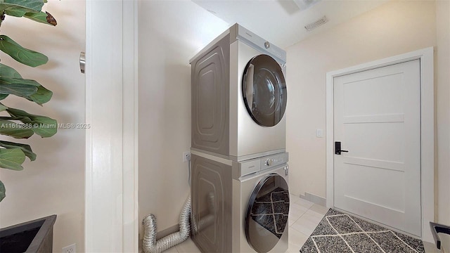 laundry area with light tile patterned floors and stacked washer / dryer