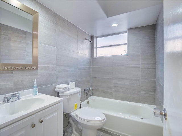 full bathroom with tile walls, toilet, vanity, and shower / washtub combination