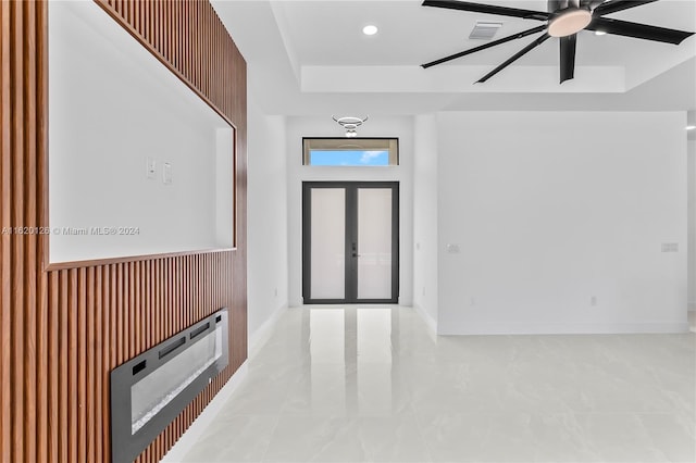 tiled entrance foyer featuring a tray ceiling and ceiling fan