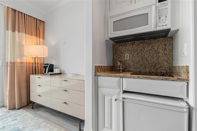 kitchen featuring tasteful backsplash, sink, white cabinets, black electric stovetop, and light stone countertops