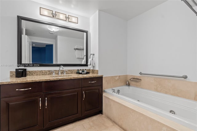 bathroom featuring tiled tub, vanity, and tile patterned flooring