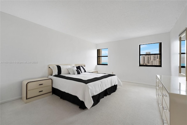 bedroom with light colored carpet, a textured ceiling, and baseboards