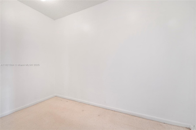 carpeted empty room featuring a textured ceiling and baseboards