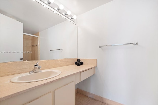 bathroom featuring a stall shower, vanity, baseboards, and tile patterned floors