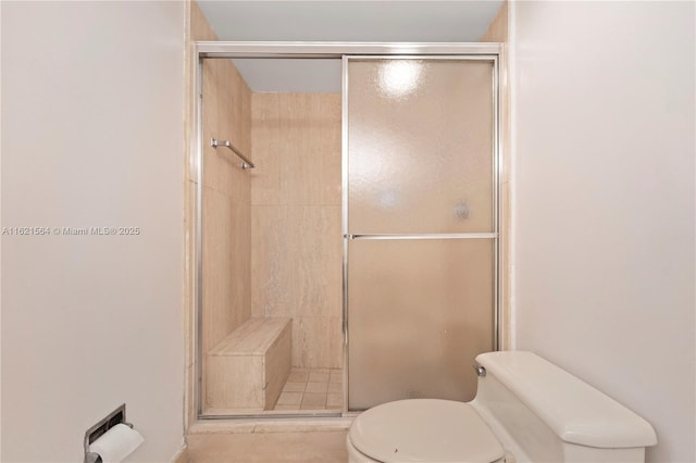 bathroom featuring toilet and a shower stall