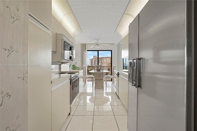 kitchen featuring range with electric stovetop, light countertops, ceiling fan, a textured ceiling, and stainless steel refrigerator