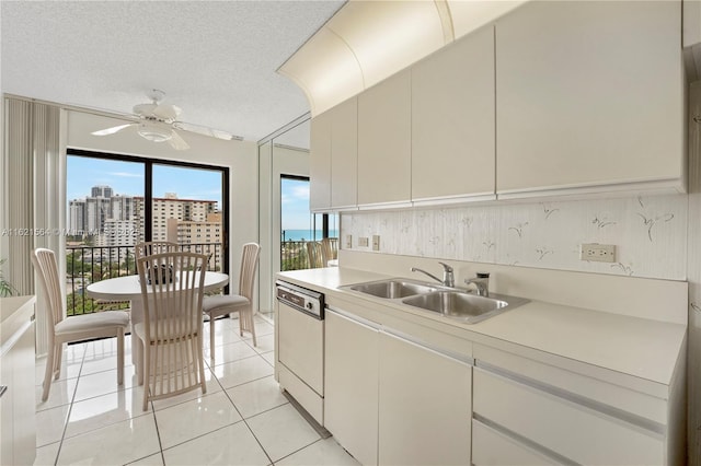 kitchen featuring light countertops, white dishwasher, a textured ceiling, a sink, and ceiling fan