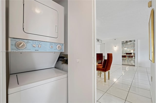 washroom with light tile patterned floors, laundry area, a textured ceiling, and stacked washer / drying machine