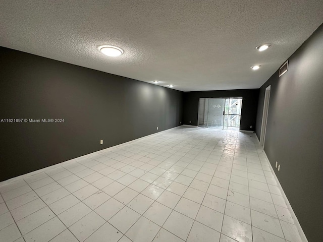 tiled empty room with a textured ceiling