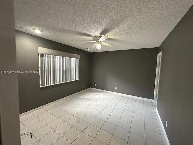 empty room featuring light tile patterned flooring, a textured ceiling, and ceiling fan