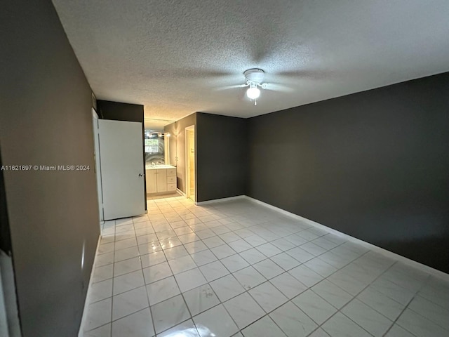 unfurnished room featuring a textured ceiling, ceiling fan, and light tile patterned floors