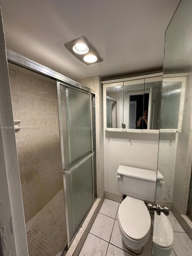 bathroom with walk in shower, toilet, and tile patterned floors