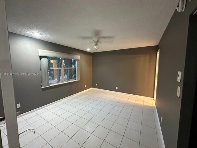 tiled spare room with a textured ceiling and ceiling fan