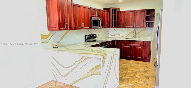 kitchen featuring decorative backsplash, light stone countertops, sink, and appliances with stainless steel finishes