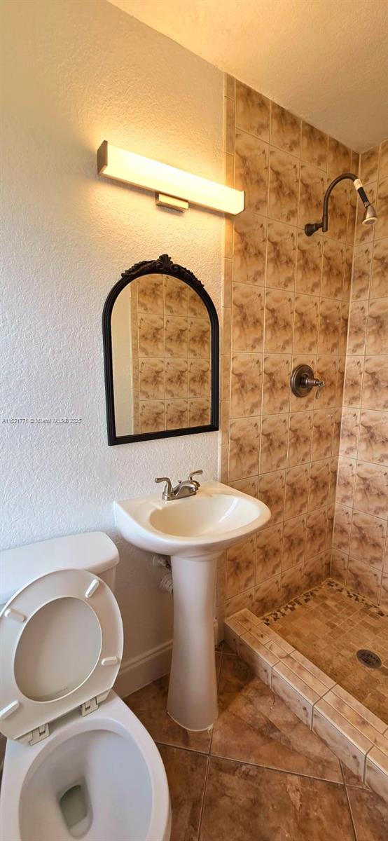 bathroom featuring a tile shower and toilet