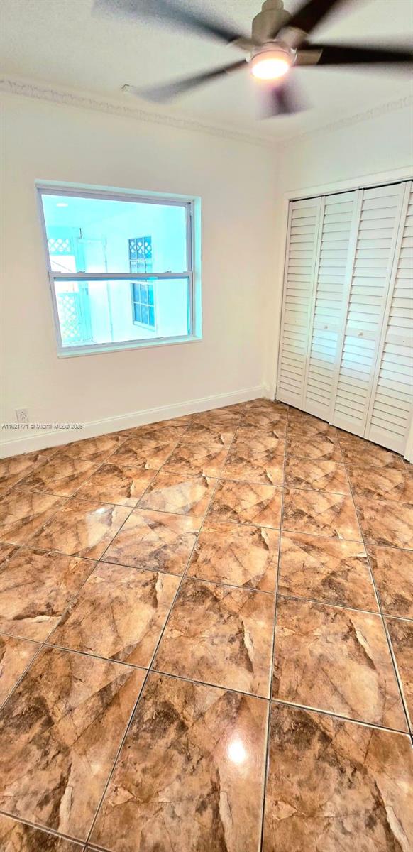 unfurnished bedroom featuring ceiling fan, multiple windows, and a closet