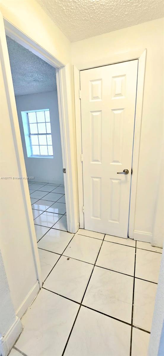 hall with light tile patterned flooring and a textured ceiling