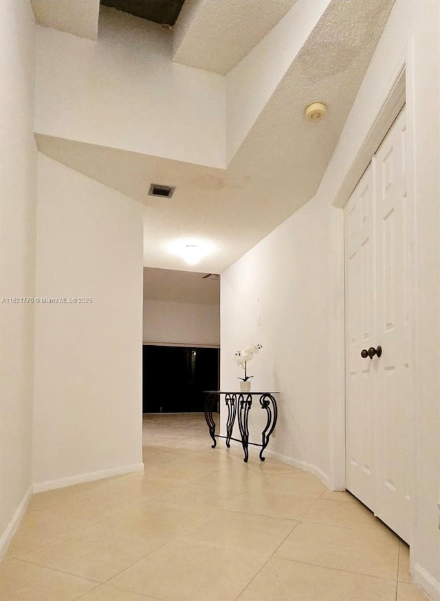 corridor with a textured ceiling and tile patterned floors