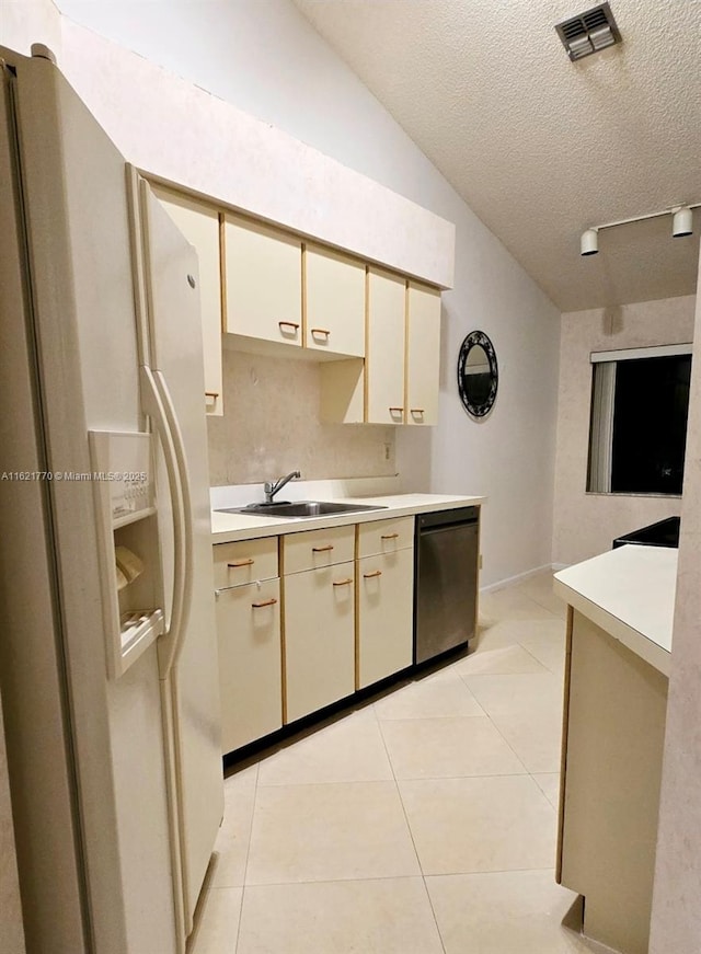 kitchen featuring sink, stainless steel dishwasher, cream cabinets, and white refrigerator with ice dispenser