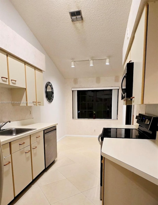 kitchen featuring sink, cream cabinetry, light tile patterned flooring, a textured ceiling, and black appliances