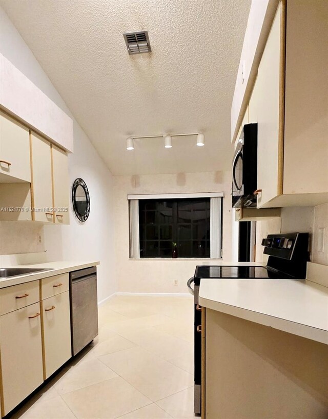 kitchen featuring black appliances, light tile patterned floors, a textured ceiling, and sink