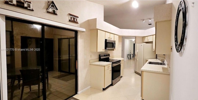 kitchen with sink, cream cabinetry, light tile patterned floors, and stainless steel appliances