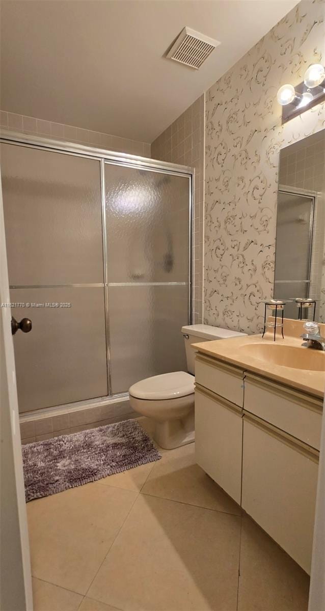 bathroom with tile patterned floors, vanity, toilet, and walk in shower