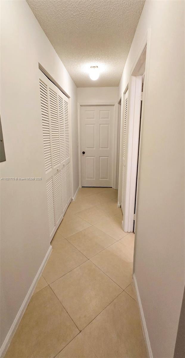 corridor featuring a textured ceiling and light tile patterned flooring