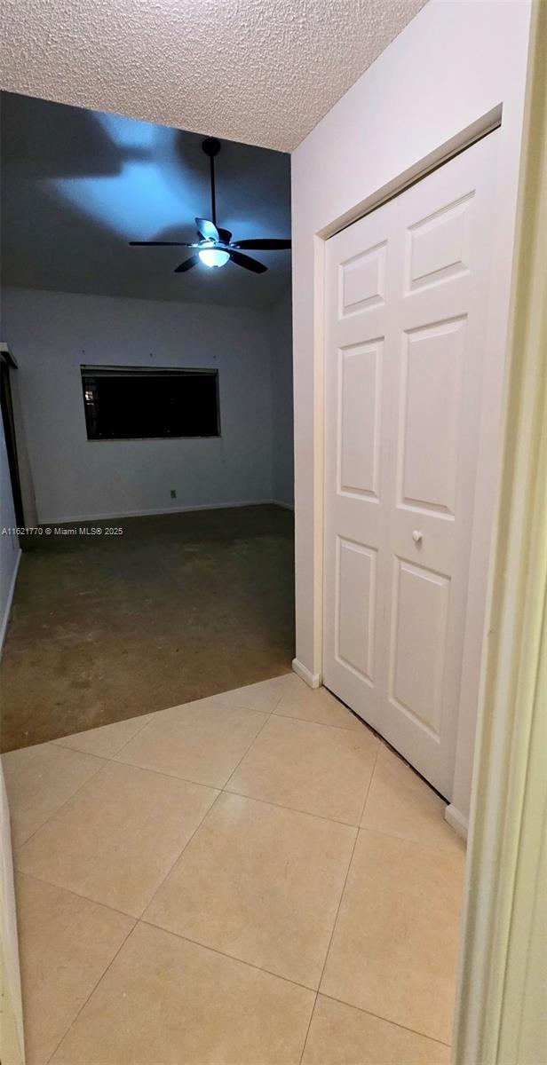 hall with a textured ceiling and light tile patterned floors