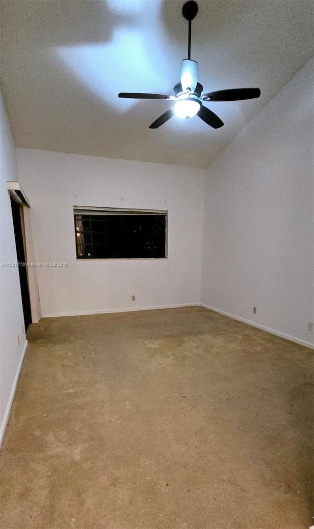 empty room featuring ceiling fan, vaulted ceiling, and light carpet