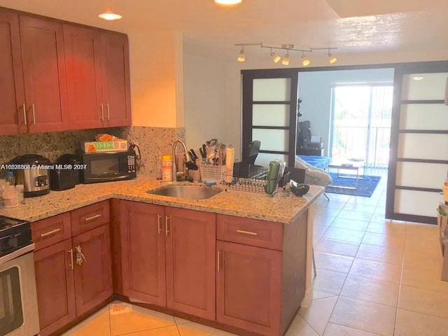 kitchen with brown cabinetry, black microwave, a sink, and a peninsula