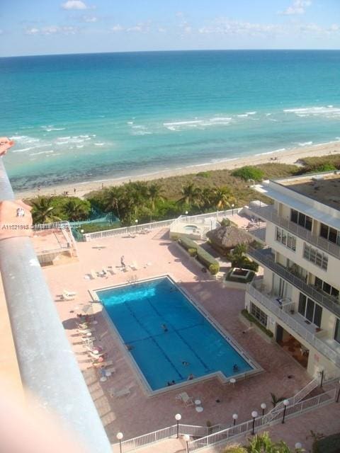 view of pool with a water view and a beach view