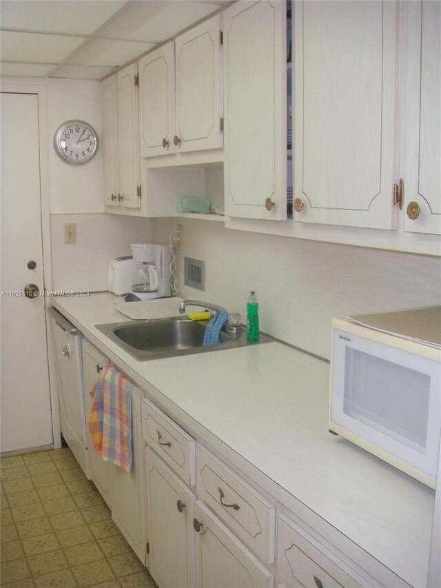 kitchen with white cabinets, light tile patterned floors, white appliances, and sink