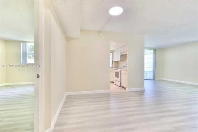 unfurnished living room with a textured ceiling and light hardwood / wood-style floors