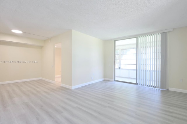 spare room with expansive windows, light hardwood / wood-style flooring, and a textured ceiling