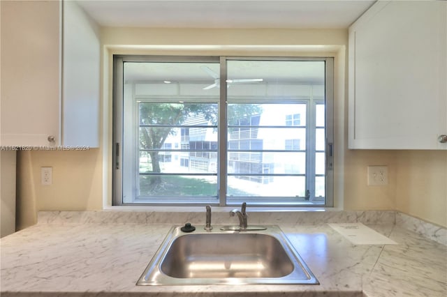 kitchen with light stone counters, sink, and white cabinets