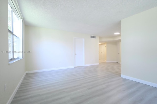 unfurnished room featuring light hardwood / wood-style flooring and a textured ceiling