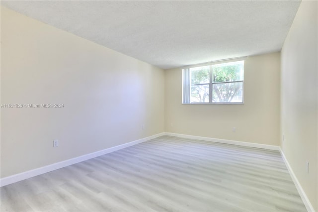 unfurnished room featuring a textured ceiling and light wood-type flooring