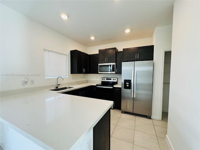 kitchen featuring light tile patterned floors, sink, dark brown cabinetry, appliances with stainless steel finishes, and kitchen peninsula